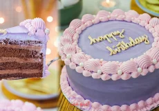 کیک تولد خانگی با اسفنج شکلاتی و روکش خامه ای بنفش و نوشته happy birthday به همراه برش کیک با فیلینگ شکلاتی