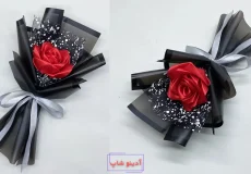 دسته گل تک شاخه رز قرمز ساخته شده با روبان ساتن و کاغذ کادو مشکی طرح‌دار